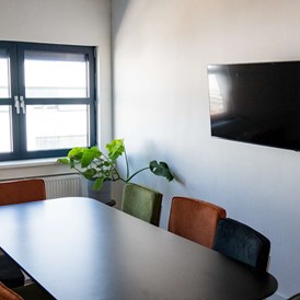 Coworking Space: Unser Besprechungszimmer inkl. Bildschirm für Präsentationen und Videotelefonie sowie einem  Whiteboard bietet Platz für 8 Personen.  - Happy House Wien