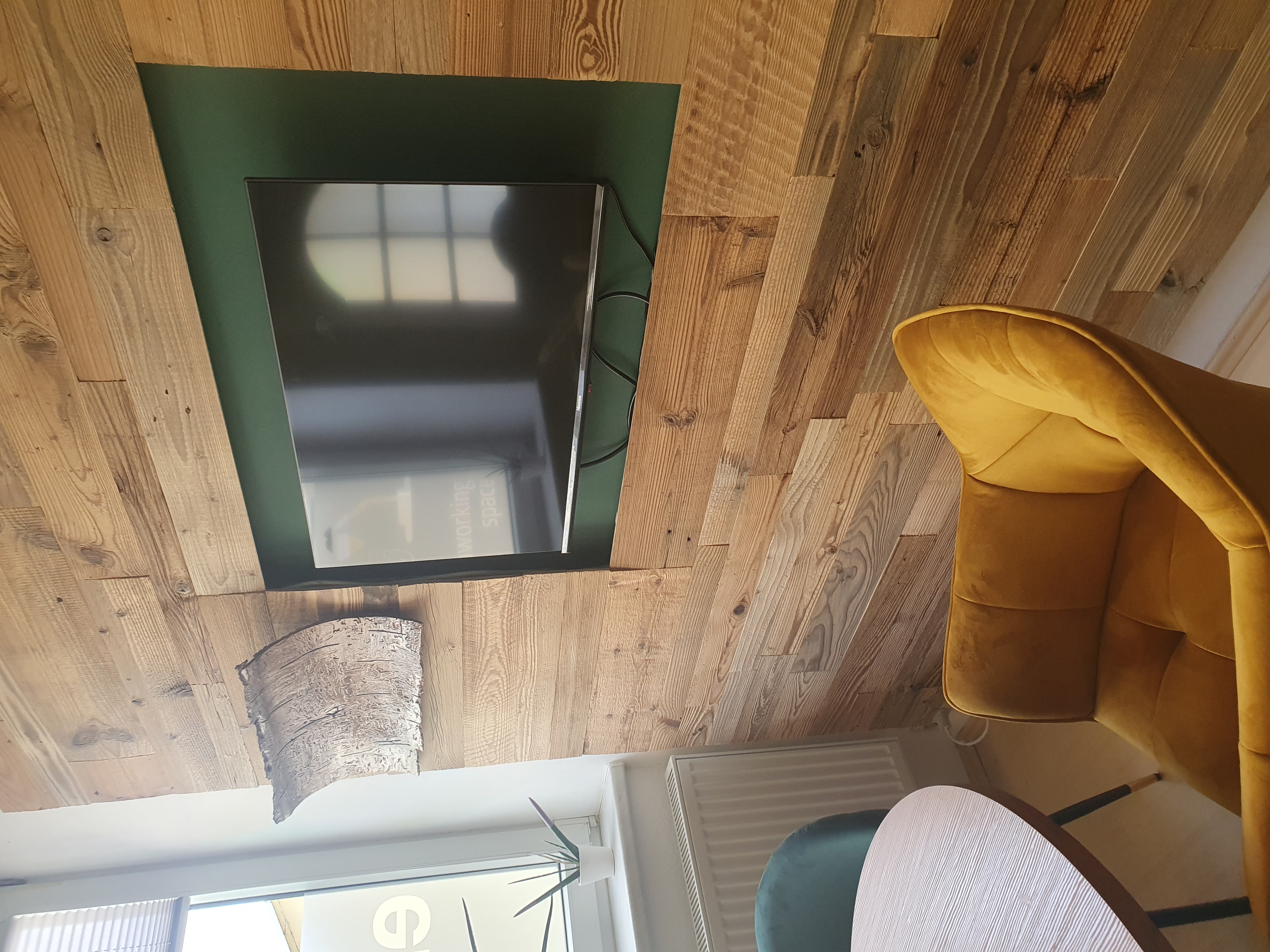 Coworking Space: Gemütlicher Meeting- und Besprechungsbereich im Coworking Space ELBLICHT in Magdeburg. Die Kombination aus nachhaltiger Holzverkleidung, großem Bildschirm und bequemen Sesseln eignet sich ideal für Präsentationen, Kundengespräche, Workshops und Teammeetings. - Elblicht 