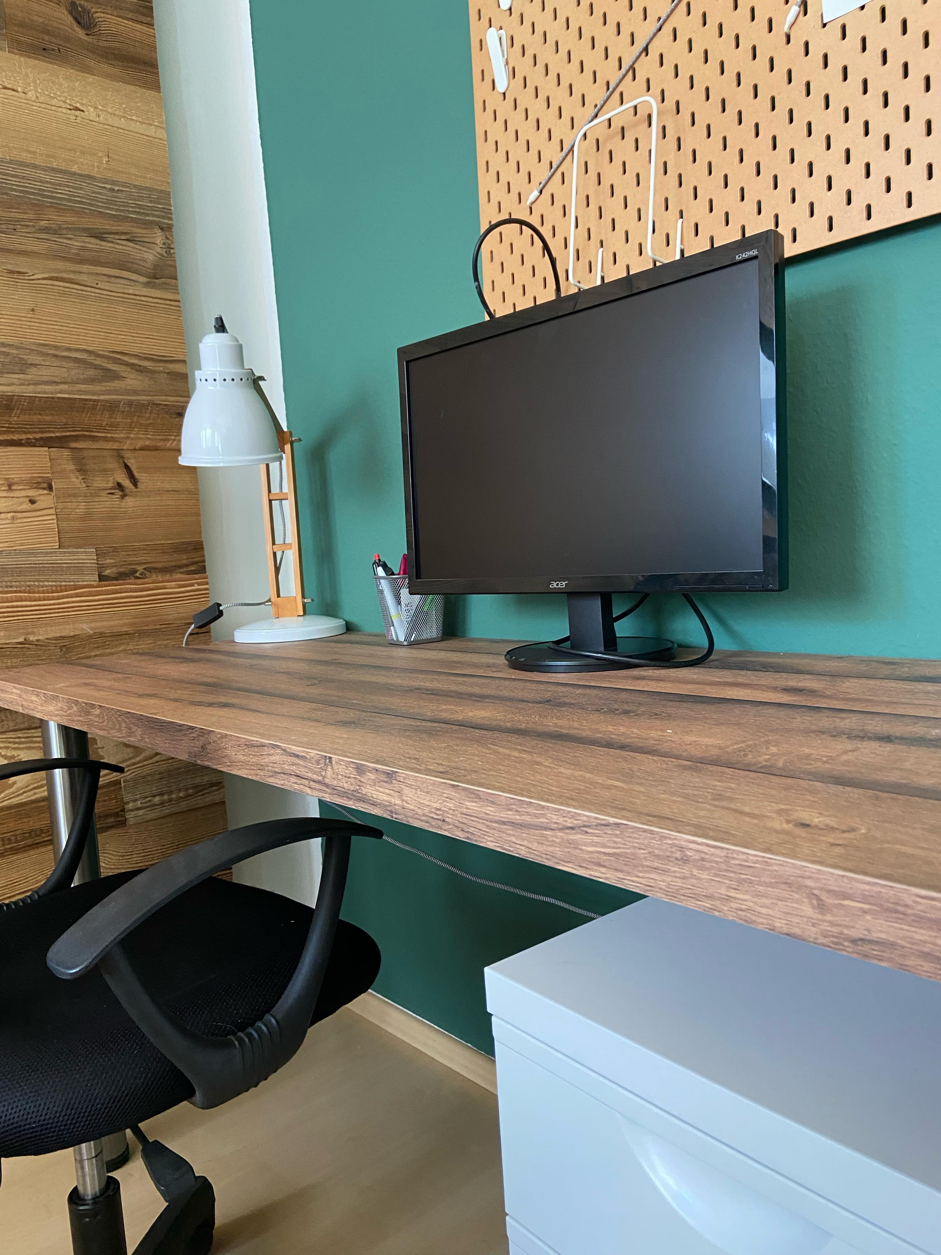 Coworking Space: Moderner Arbeitsplatz mit großzügiger Arbeitsfläche, externem Monitor, Schreibtischlampe und Rollcontainer. Das Büro verbindet funktionale Ausstattung mit natürlichem Holzdesign und bietet eine professionelle Arbeitsumgebung für Selbstständige und kleine Teams. - Elblicht 